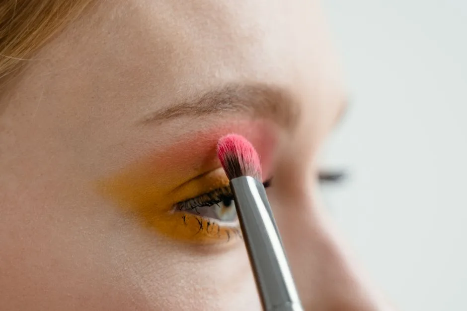 Person applying vibrant eye shadow with a makeup brush for a colorful look.
