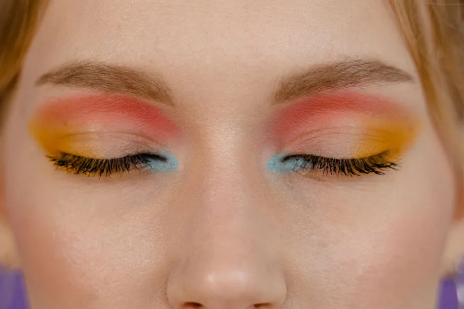 Close-up of a woman's closed eyes showcasing vibrant multicolored eye makeup.