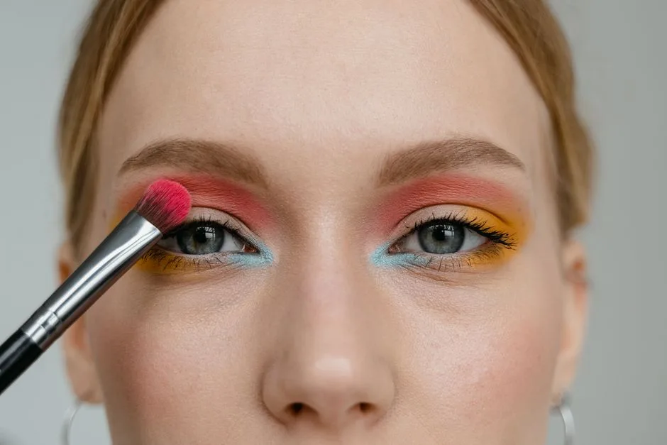 A woman applying vibrant multicolored eye makeup with a brush, showcasing artistry and precision.