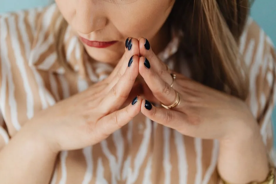 Close-up of a woman with steepled fingers and thoughtful expression, showcasing focus.