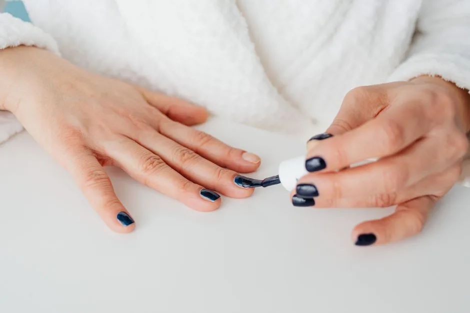 Close-up of a woman applying dark nail polish for a stylish manicure.