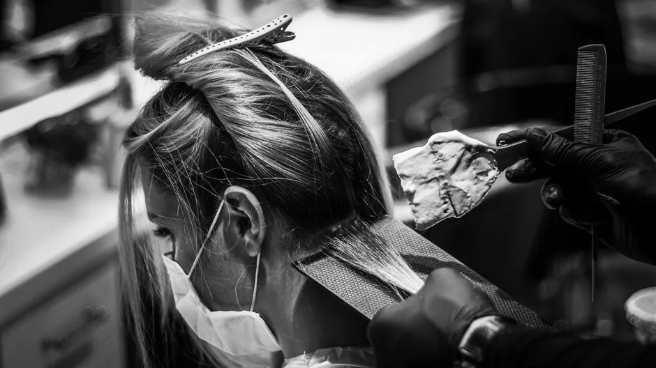 Monochrome image of a woman getting her hair colored in a salon.
