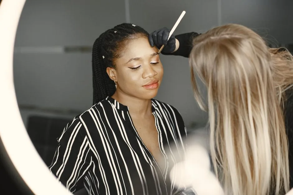 Makeup artist applying cosmetics to a woman in a stylish studio environment.