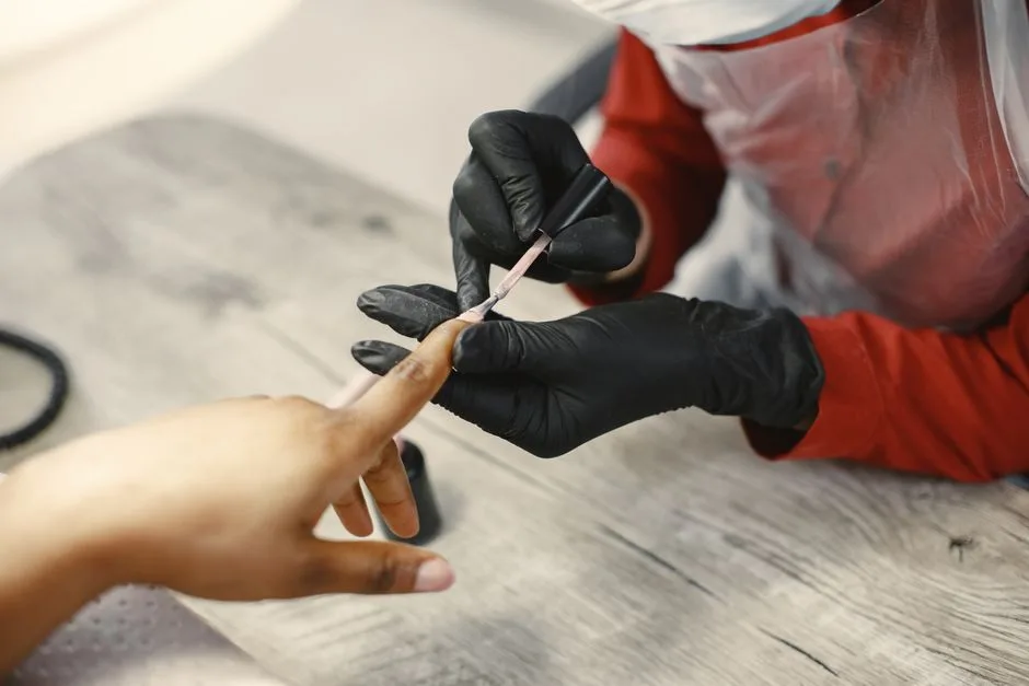 A nail artist carefully applies nail polish to a client's nails in a salon setting, using precise techniques.