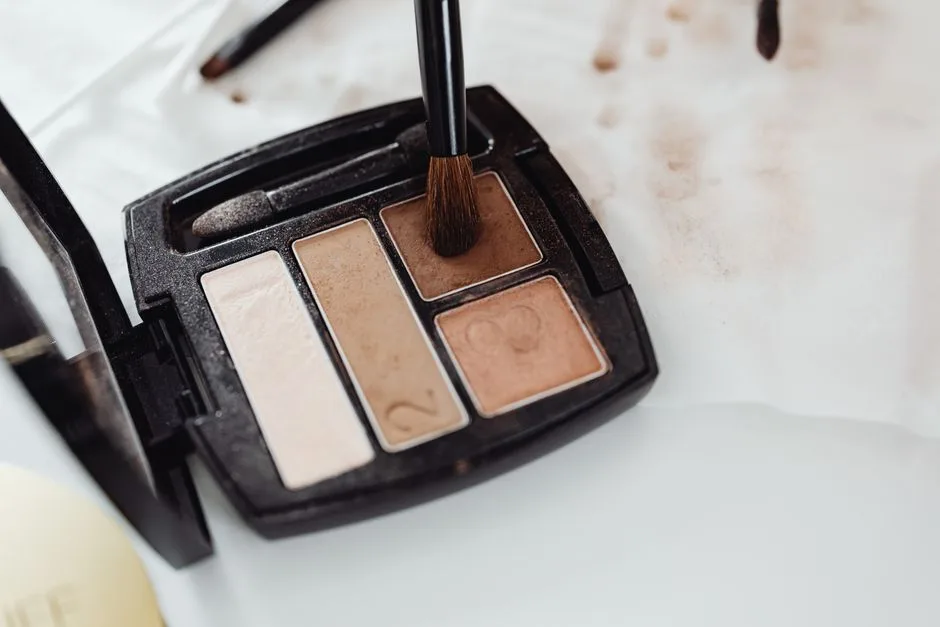 Close-up of a makeup eyeshadow palette in neutral shades with a brush touching the product surface.