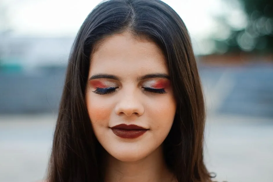 Close-up portrait of a woman with vibrant red and blue eye shadow and bold lipstick.