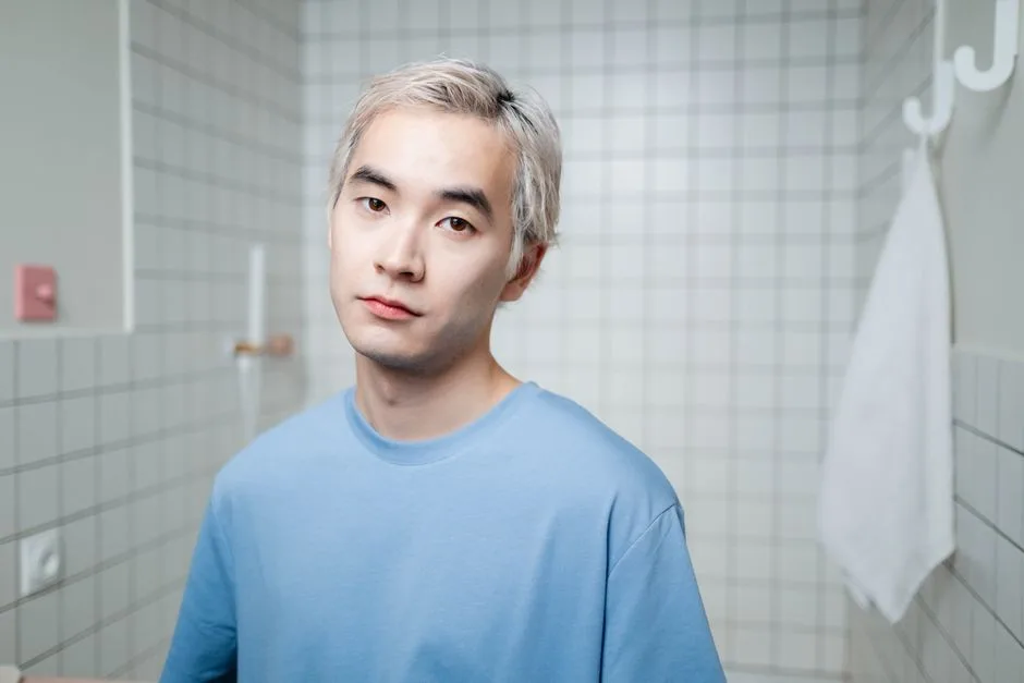 Portrait of a young man with blonde hair in a contemporary bathroom setting, exhibiting confidence.
