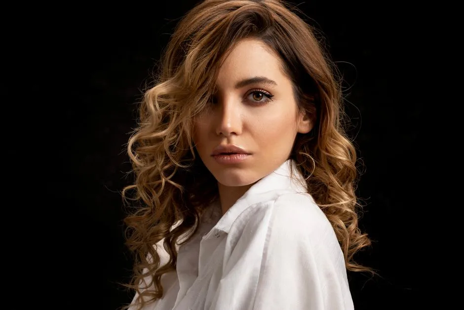 Elegant portrait of a brunette woman with curly hair and a calm expression in a studio setting.