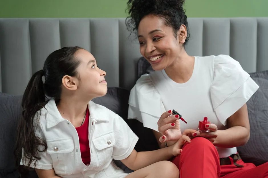 A joyful mother and daughter enjoying quality time painting nails together.