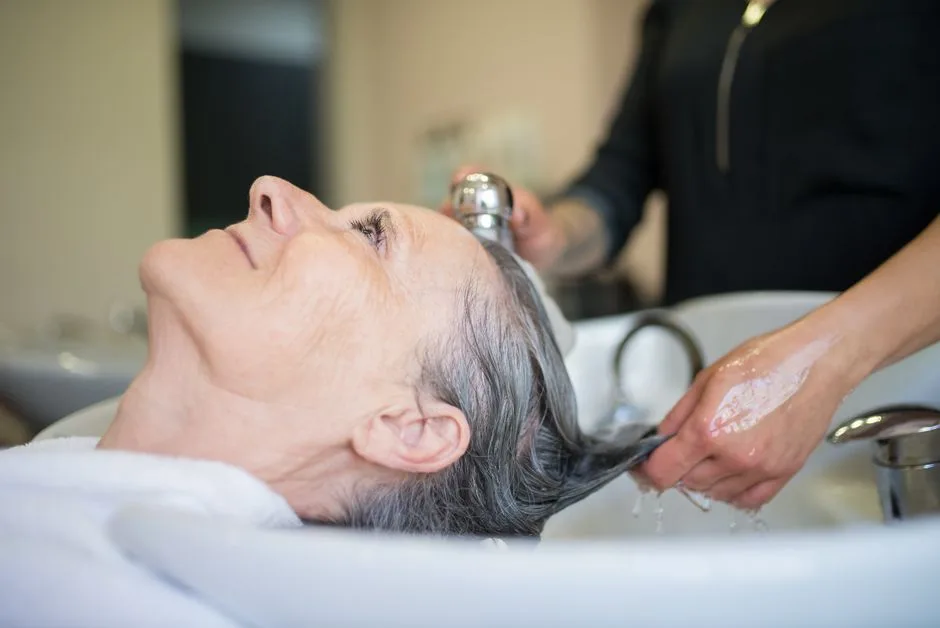 Elderly woman enjoying a relaxing hair wash session in a professional salon setting.