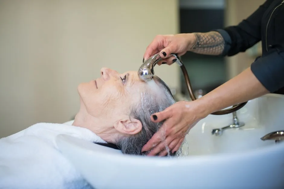 Elderly woman receiving a relaxing hair wash in a salon setting.