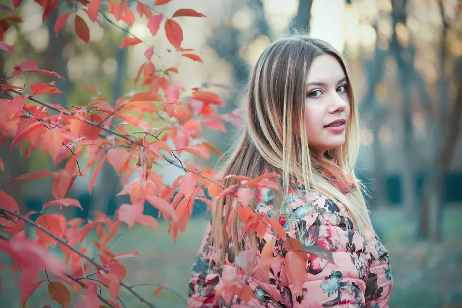 Portrait of a young woman with autumn leaves, looking back, in a seasonal outdoor setting.