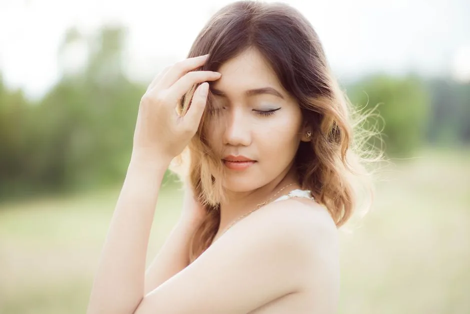 Elegant woman with closed eyes posing gracefully in a natural setting.