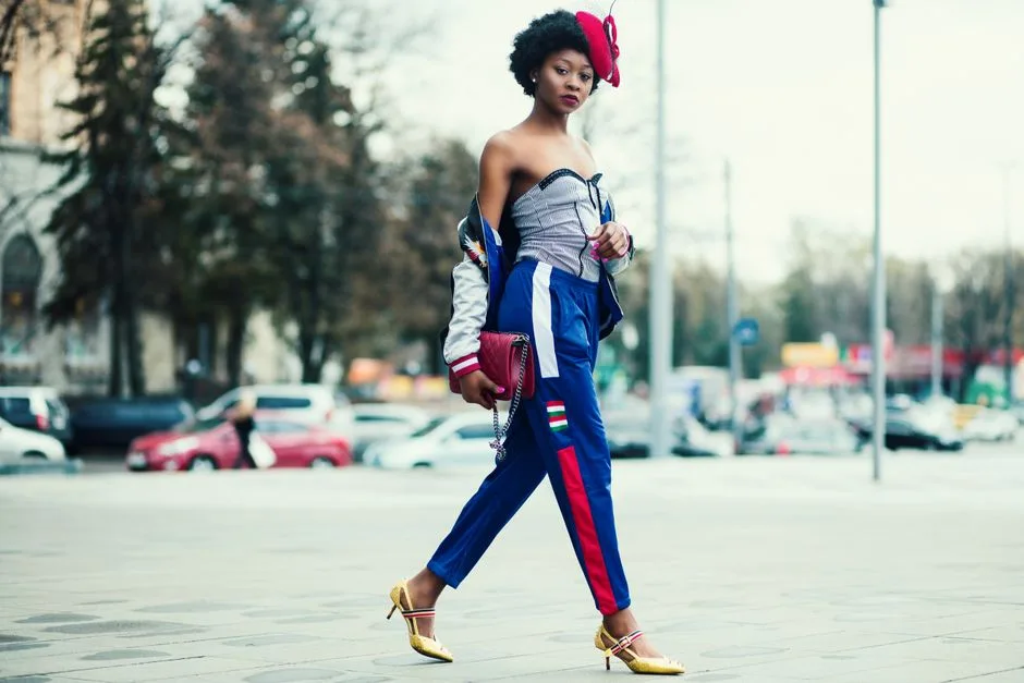 Stylish woman in vibrant outfit walking confidently in cityscape environment.