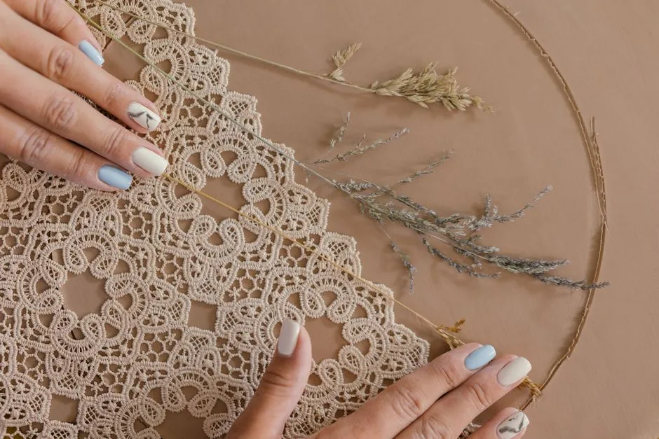 A close-up of handmade lace creation with delicate hands and colorful nails, showcasing intricate craftsmanship.