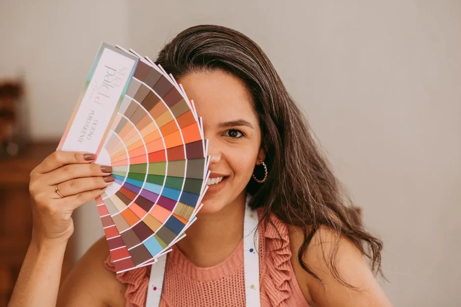 A smiling woman holds a color palette, perfect for creative and design themes.