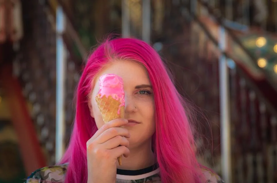 A woman with vibrant pink hair holding an ice cream cone with melted pink ice cream.
