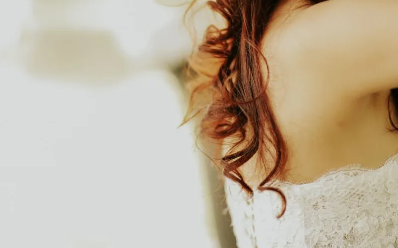 Close-up of a bride's delicate lace dress and elegant curly hairstyle, capturing wedding elegance.
