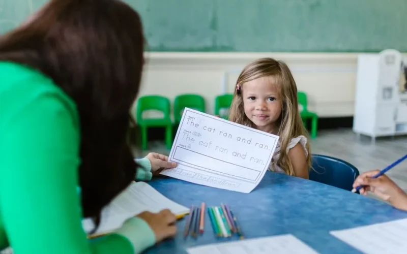 A young girl participates in an engaging classroom activity with her teacher.