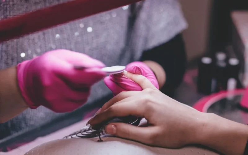 Close-up of a professional manicure session with pink gloves and a nail file in an indoor salon.