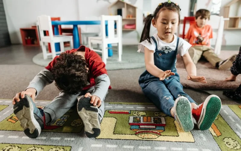 Young children stretching and exercising together in a kindergarten classroom.