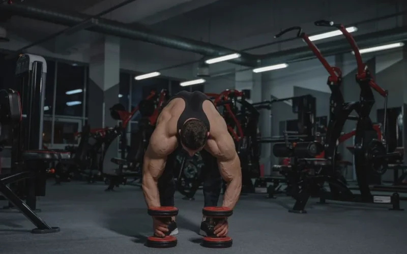 Muscular man in a gym lifting heavy dumbbells showcasing strength and fitness.