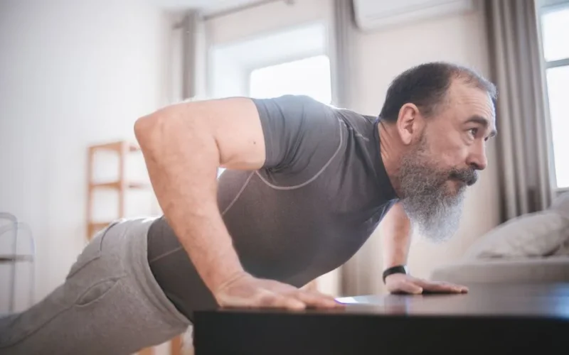 Elderly man performing push-ups in his living room for fitness and health.