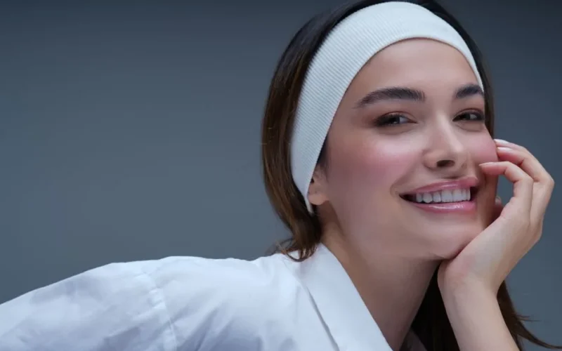 A confident woman smiling while wearing a white headband, conveying positivity and beauty.