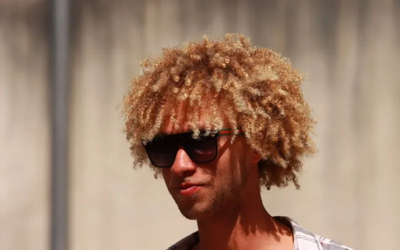 Headshot of a blonde man with curly hair wearing sunglasses outdoors in Florence, Italy.