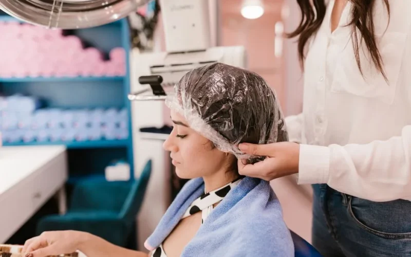 A woman enjoys a relaxing hair treatment at a modern salon with attentive care.