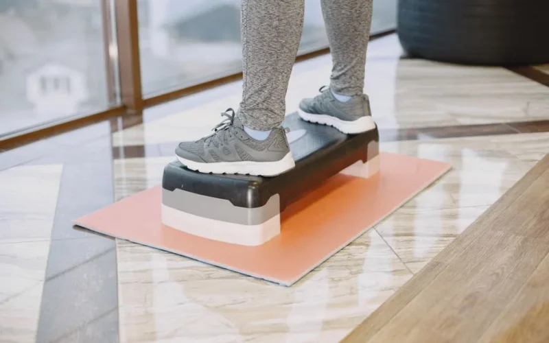 A person exercising indoors using a step platform for a workout routine.