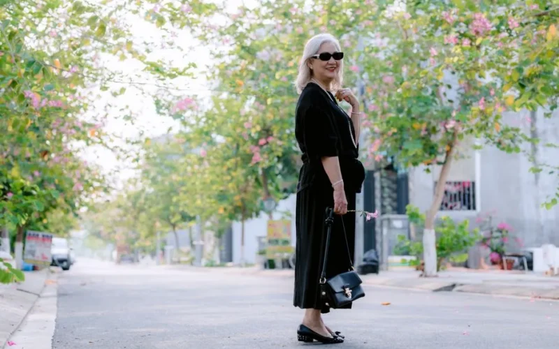 Sophisticated woman strolling down a flower-lined street in springtime.