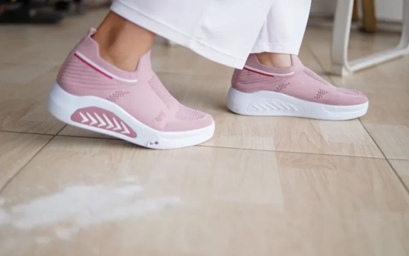 Close-up of fashion-forward pink sneakers worn indoors on a wooden floor.