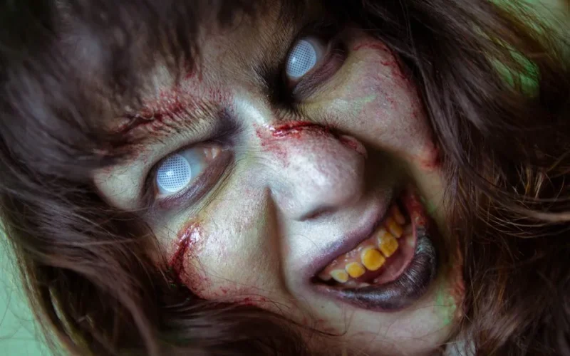 Frightening close-up of a zombie with white eyes and gory makeup, perfect for Halloween themes.