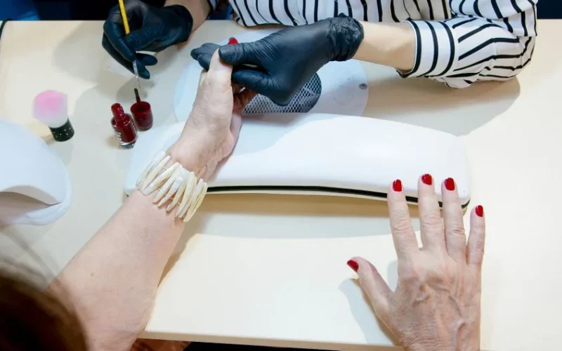 Top view of a professional manicure session with red nail polish application in a modern salon.