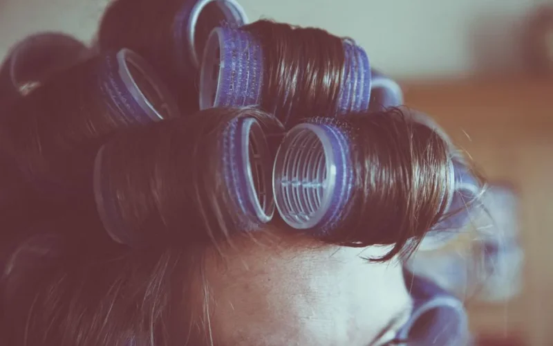 Vintage-style close-up of a woman's hair in curlers, emphasizing retro hair styling.