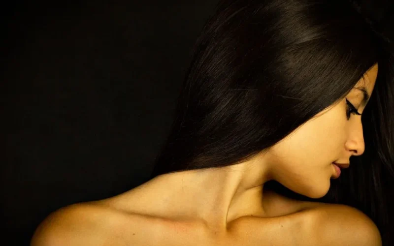A serene portrait of a woman with long dark hair, highlighting her graceful profile and smooth skin.