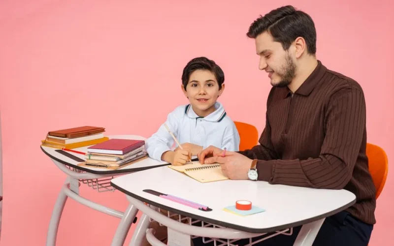 A father assists his young son with homework at a desk in Yalova, Türkiye.