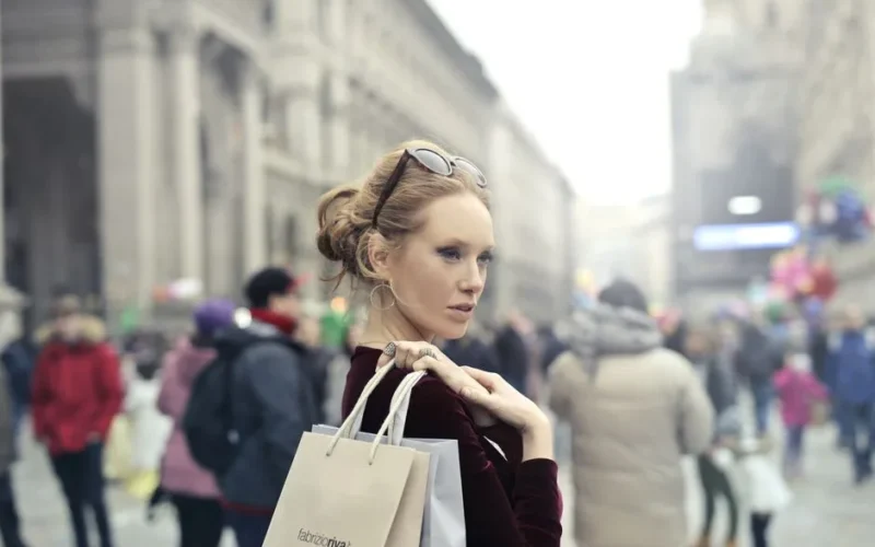 Stylish woman with shopping bags in bustling Milan street, embracing urban fashion vibes.