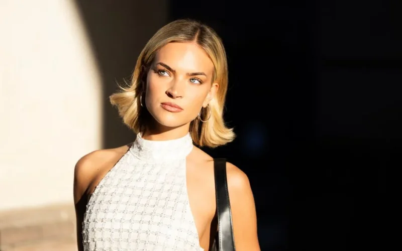 Fashionable woman with blonde hair poses elegantly in a sunlit portrait, showcasing style and sophistication.