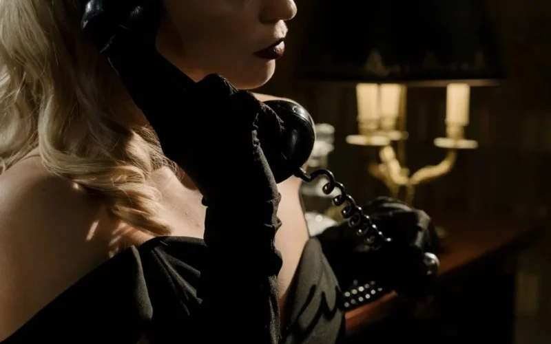 Elegant woman in vintage noir style holding a phone, exuding mystery and sophistication.