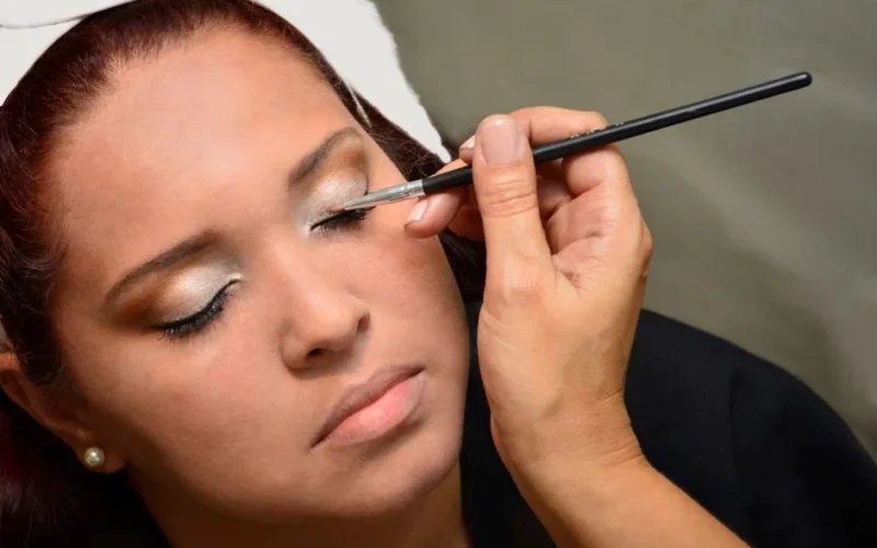 Close-up of a woman having eye makeup applied, highlighting beauty and precision.
