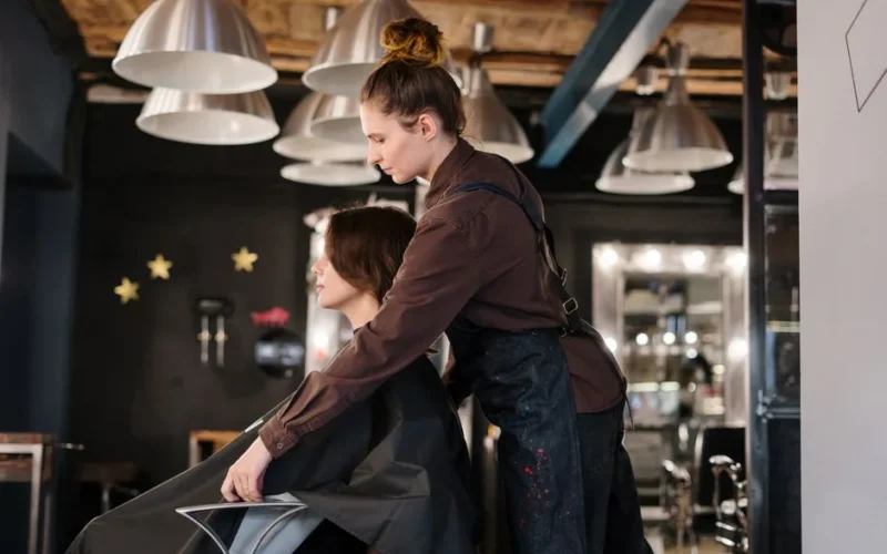 Hairdresser styling a client's hair in a contemporary salon setting.