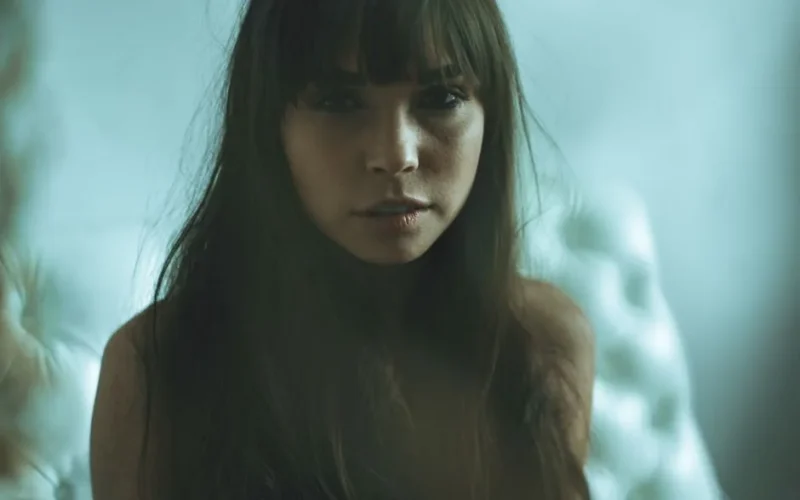 Artistic portrait of a woman with long hair and bangs in a soft, moody setting.