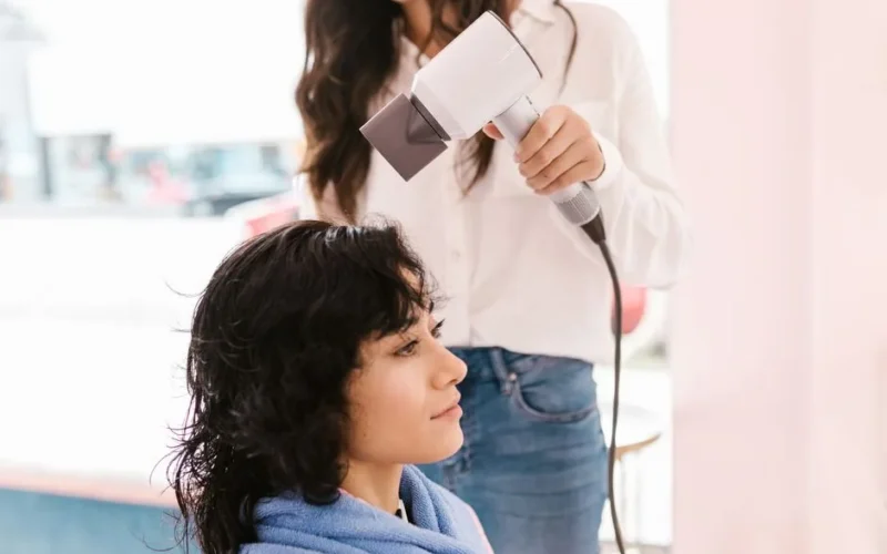 A woman receives a professional hairstyle in a salon with a focus on client and hairdresser interaction.