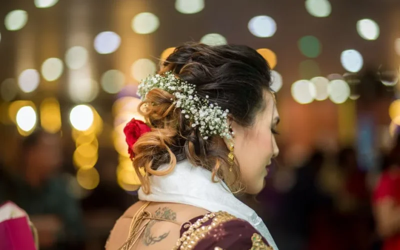 Close-up of a bridal hairstyle adorned with flowers and elegant jewelry at a festive event.