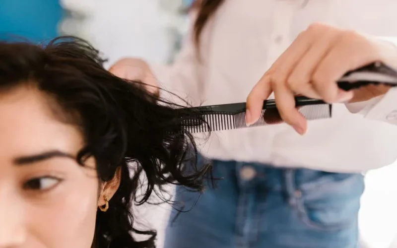 Close-up of hairstylist cutting client's hair in a salon setting.