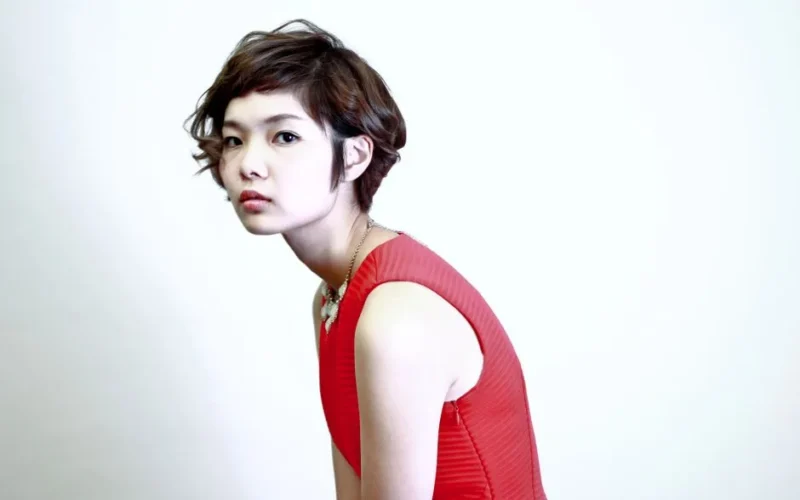 Elegant portrait showcasing a young woman with short hair in a vibrant red dress, exuding modern fashion.
