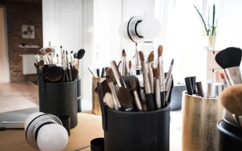 A collection of makeup brushes neatly organized in stylish holders on a vanity table with natural light.
