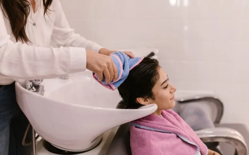 A woman enjoys a relaxing hair wash at a modern hair salon, emphasizing self-care and pampering.